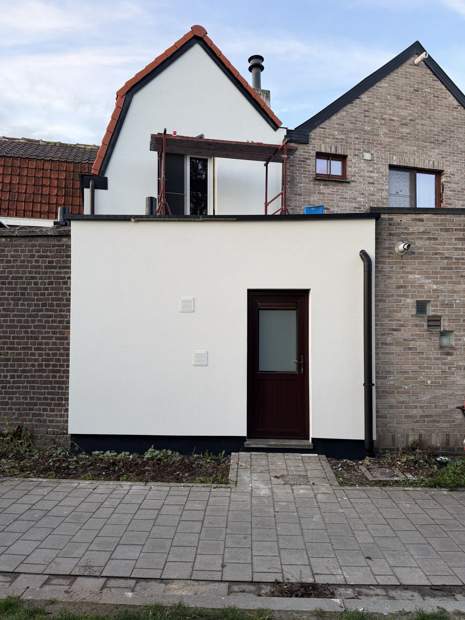 De achtergevel in Oostakker na de werken, witte crepi en zwarte plint onder het nieuwe pannendak