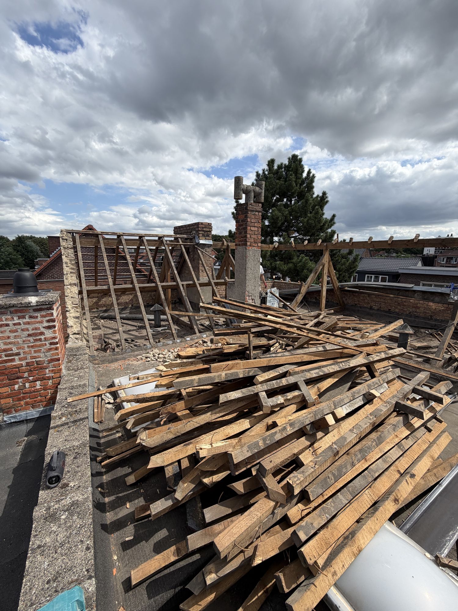 De oude houten dakstructuur van het hoekgebouw in Gent afgebroken, met de balken op een stapel