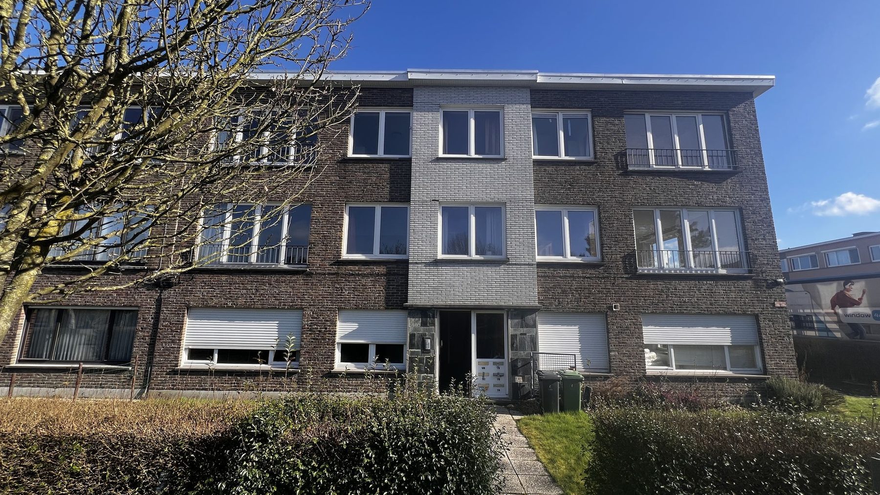 Het appartementsgebouw in Gent voor de renovatie, met de verweerde baksteengevel en de oude witte ramen