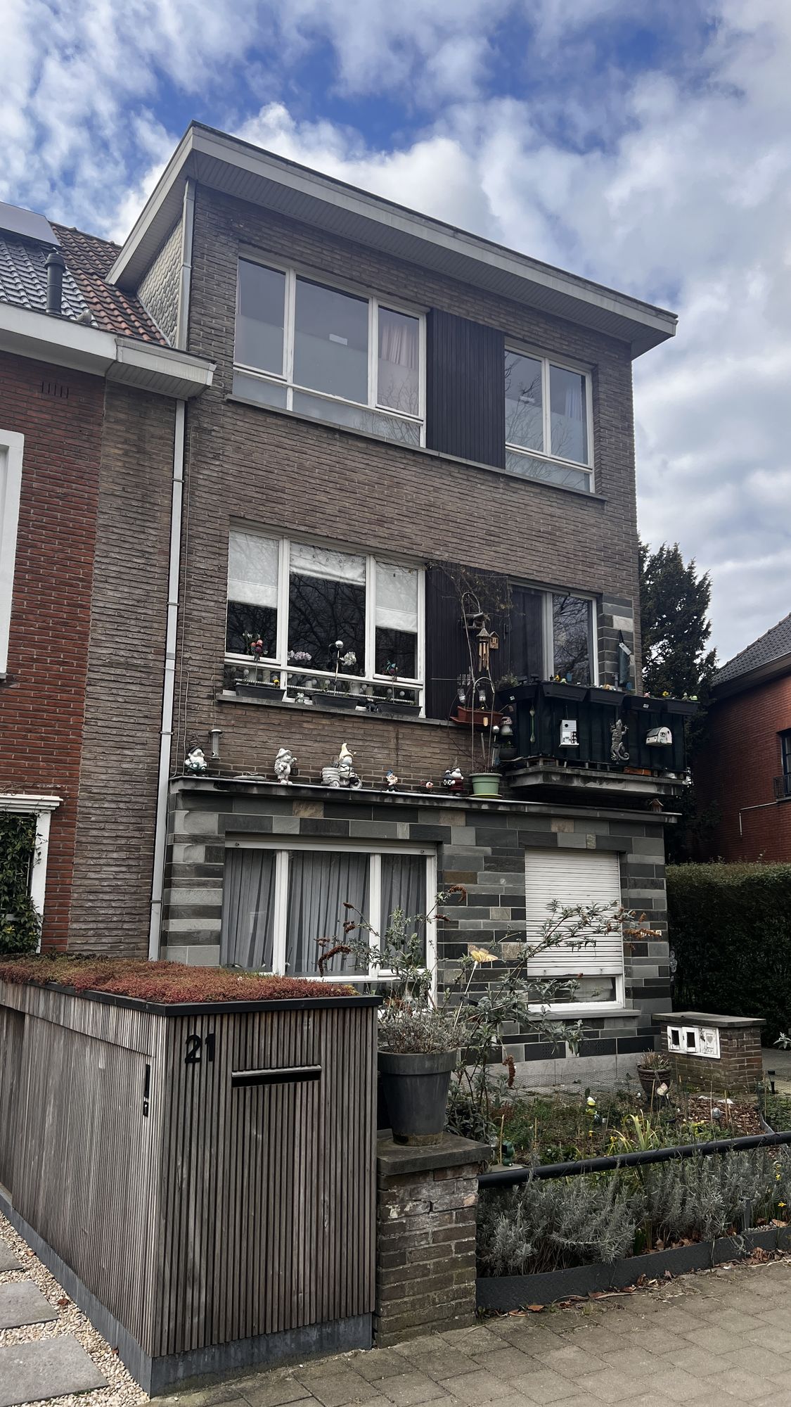 Het appartementsgebouw in Gent voor de renovatie, met de oude baksteengevel, de donkere plint en het oude schrijnwerk
