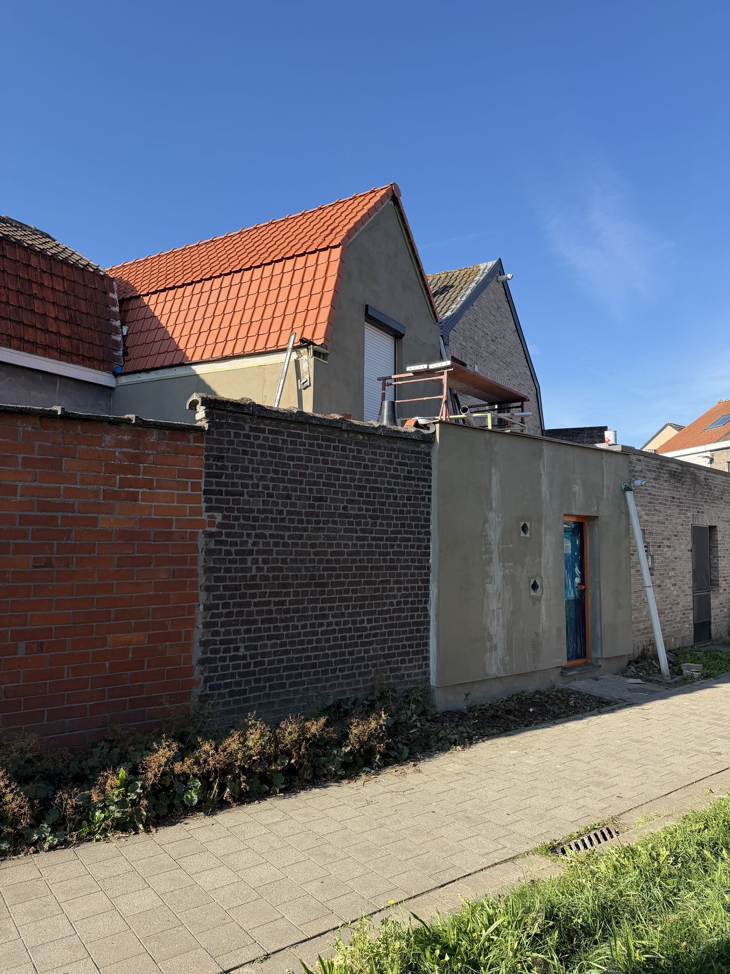 Achterzijde in Oostakker met de grondlaag van de crepi op de aanbouw en het nieuwe pannendak erboven