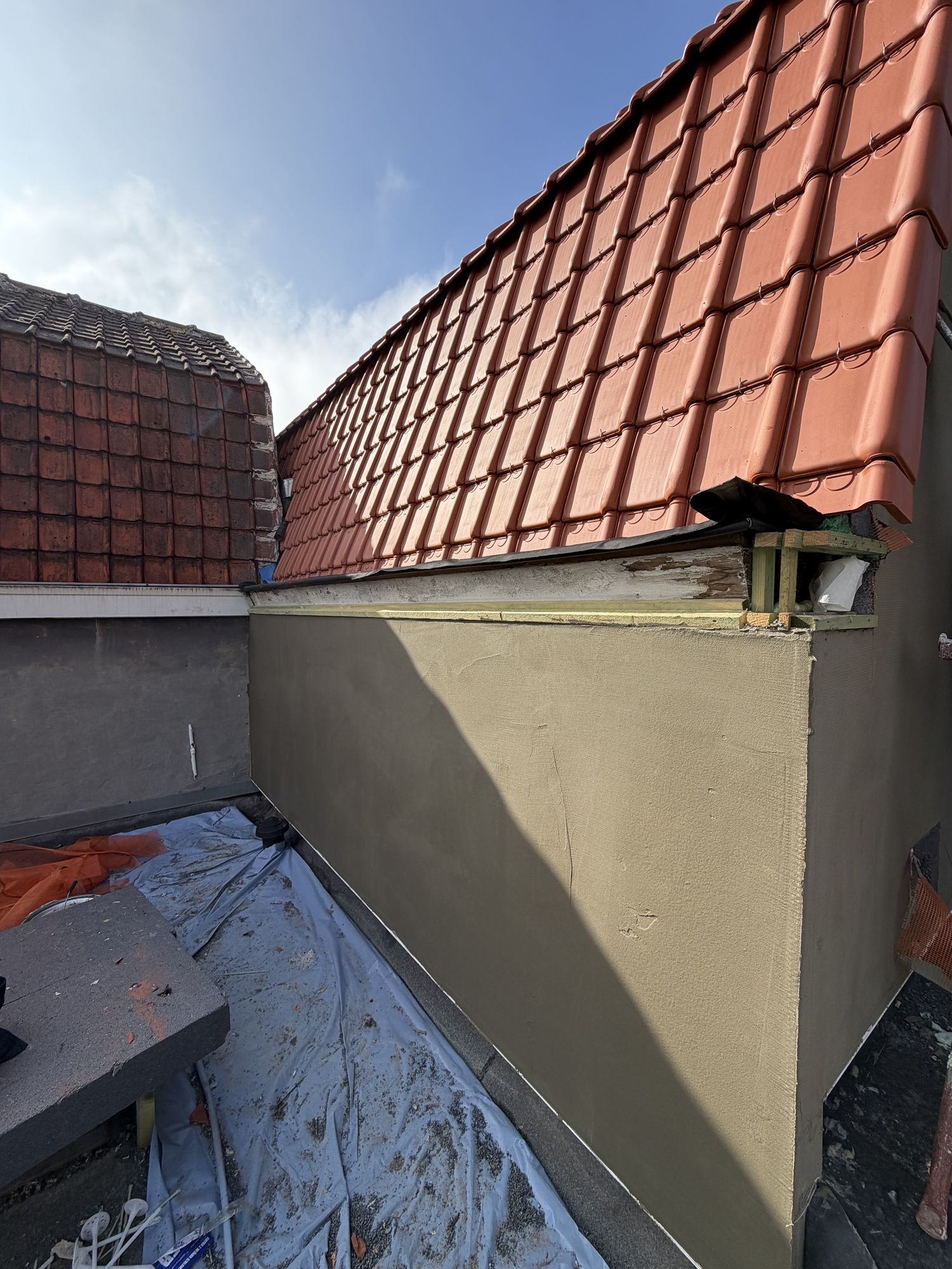 De grondlaag van de crepi op de aanbouw in Oostakker, aangewerkt tegen de nieuwe dakrand