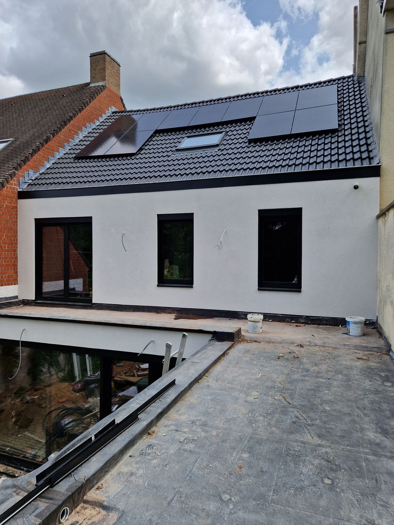 De geisoleerde gevel met crepi in Oostrozebeke, naast de onbehandelde baksteengevel van de buren
