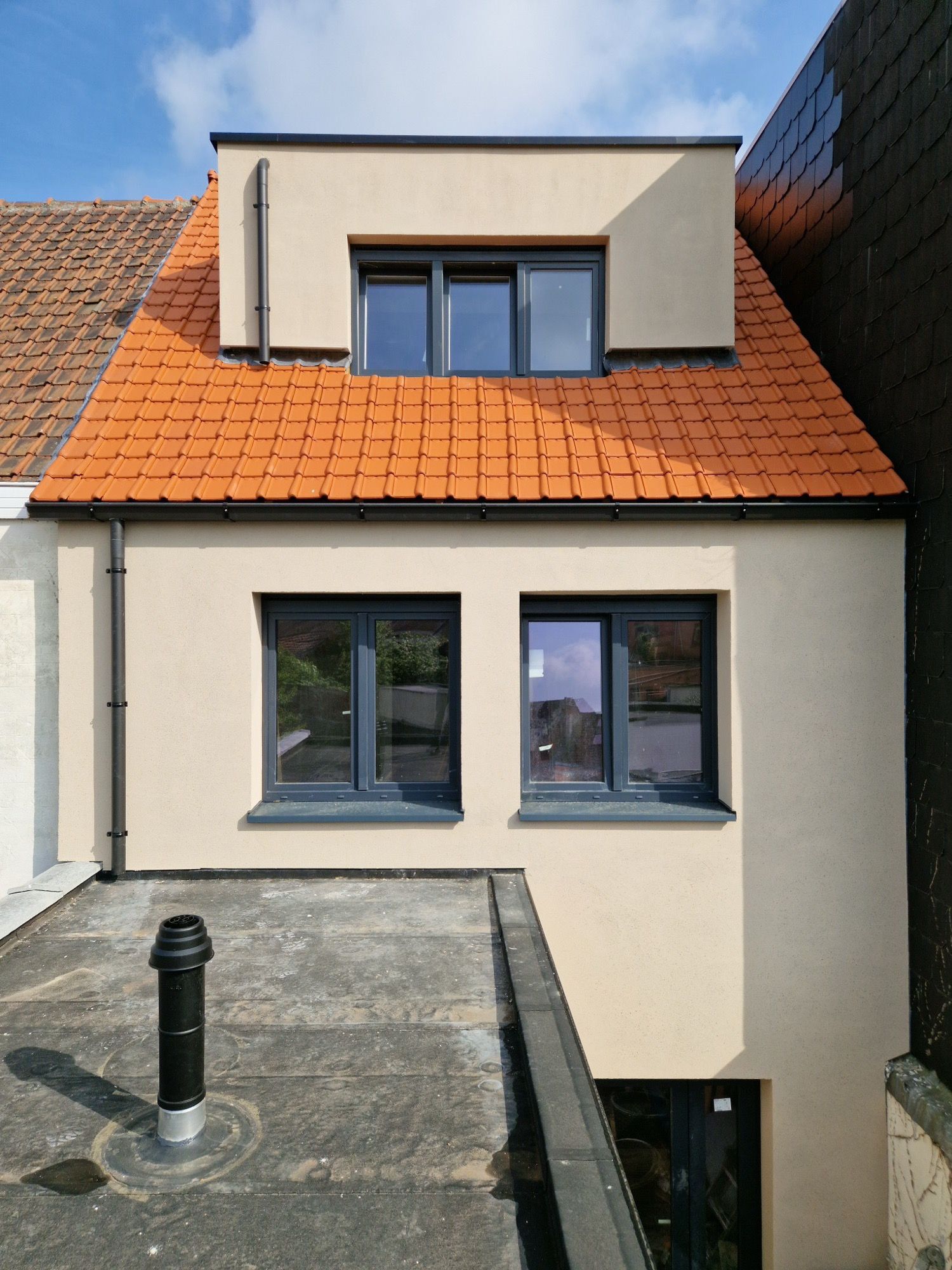 Achtergevel van de woning na de renovatie, afgewerkt in sierpleister