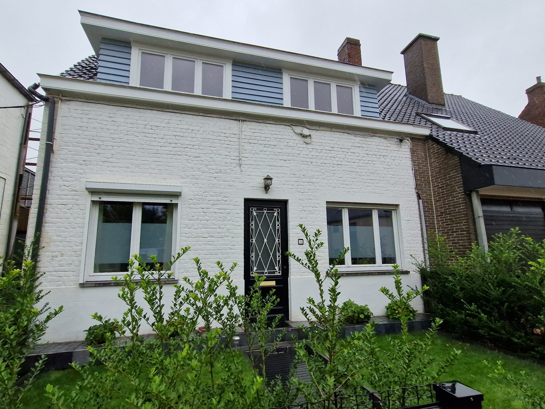 De halfopen woning in Evergem voor de werken, met de wit geschilderde gevel