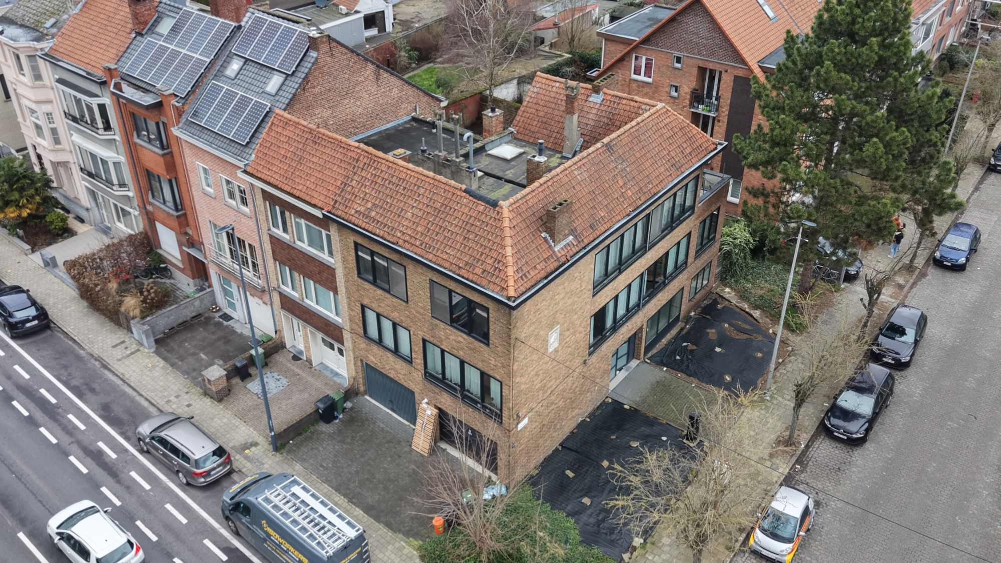 Het hoekgebouw in Gent voor de werken, met gele baksteen en een oranje pannendak, gezien vanuit de lucht