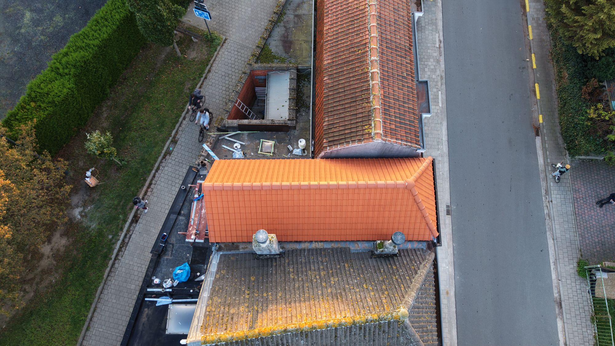 Luchtfoto in Oostakker van het nieuwe rode pannendak naast het oude, vermoste dak van de buren