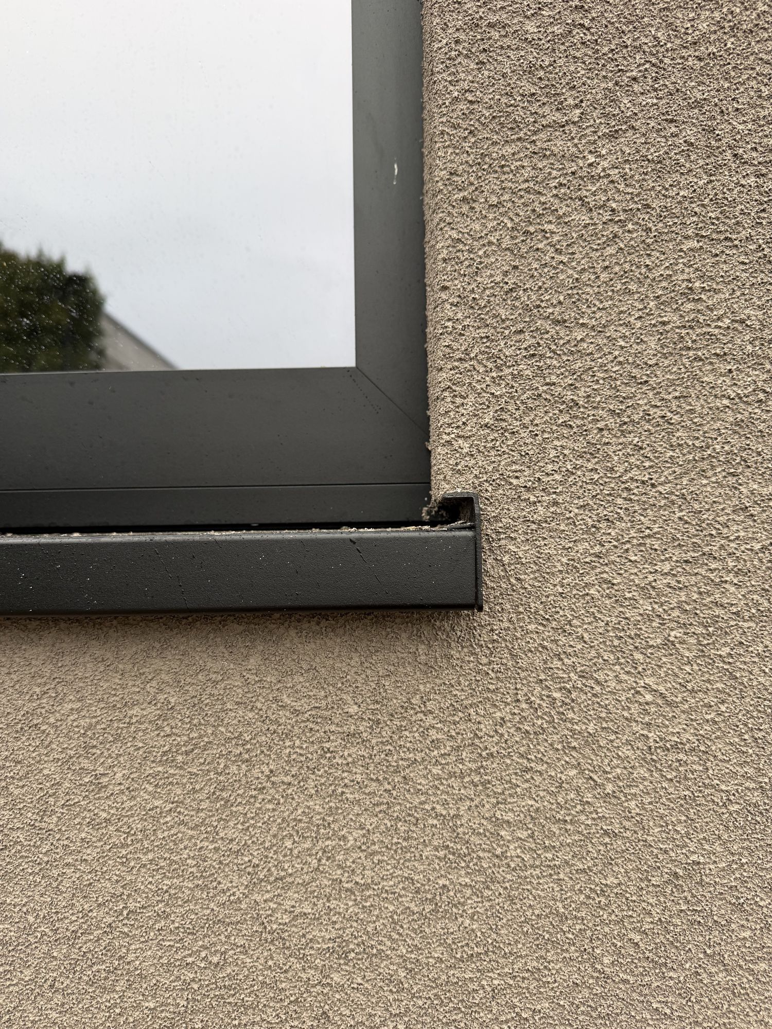 Detail van een zwarte raamdorpel in Brakel met de korrelstructuur van de spuitkurk er net onder