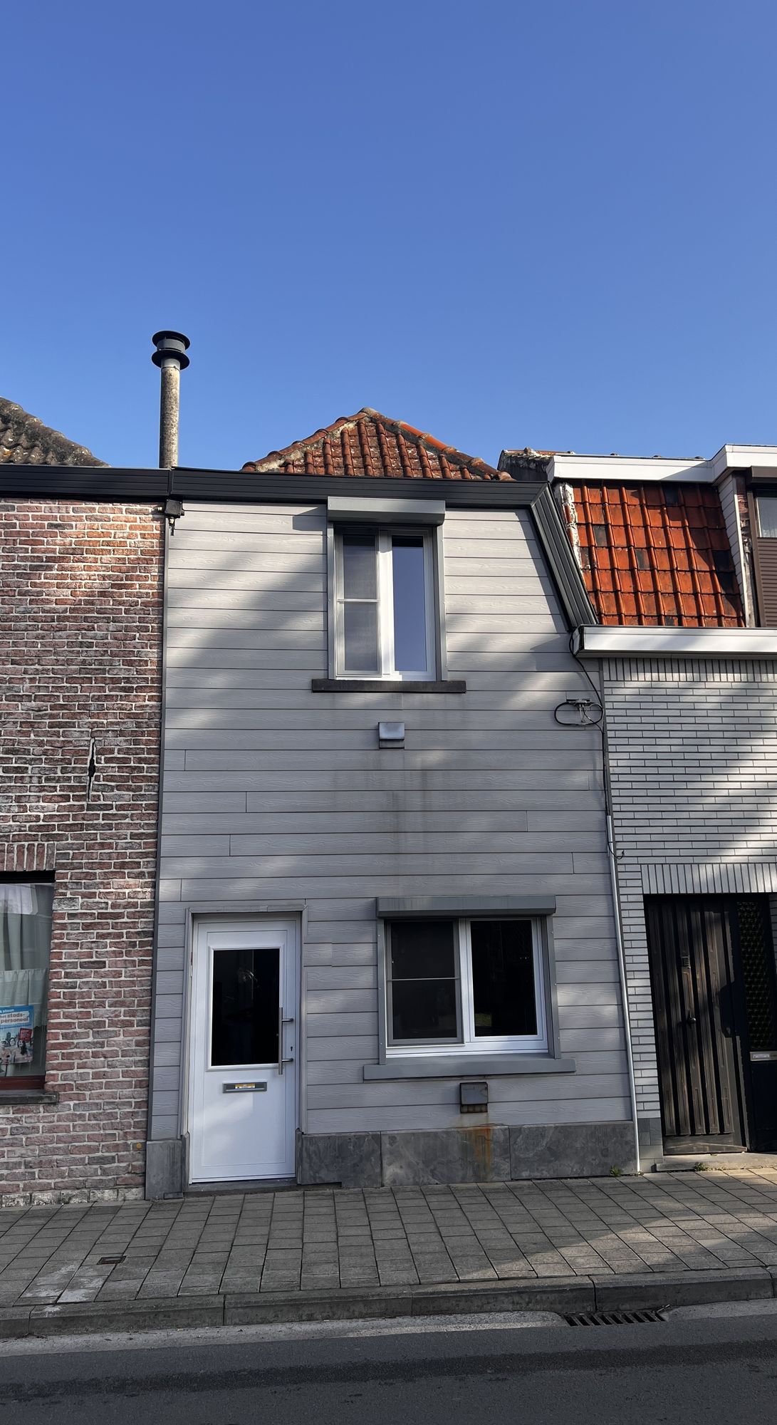 De voorgevel van de rijwoning in Oostakker voor de werken, bekleed met grijze horizontale gevelplanken