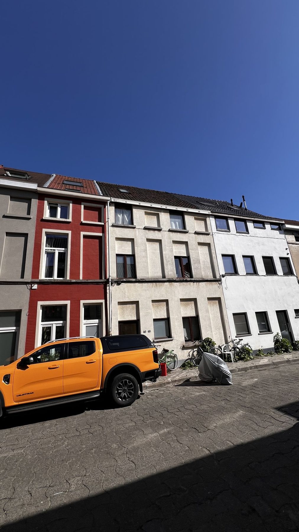 De Gentse rijwoning voor de renovatie, met verweerde cementering en de oude donkere dakbedekking