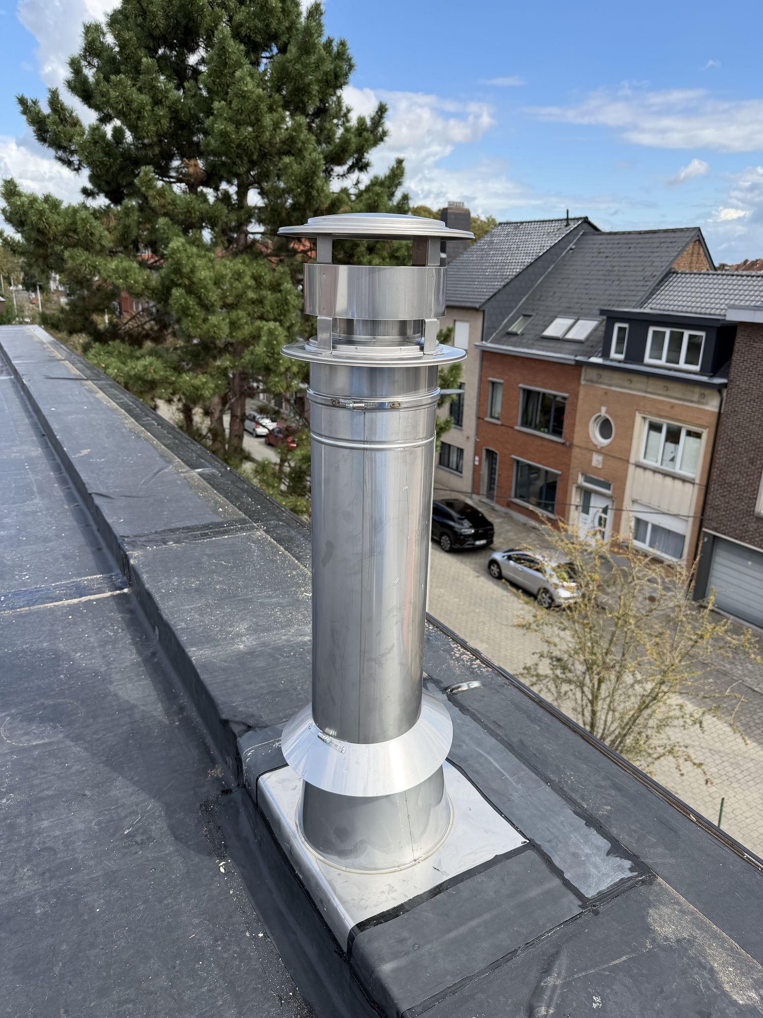 Inox rookgasafvoer met kraag tegen de opgehoogde dakrand van het platte dak in Gent