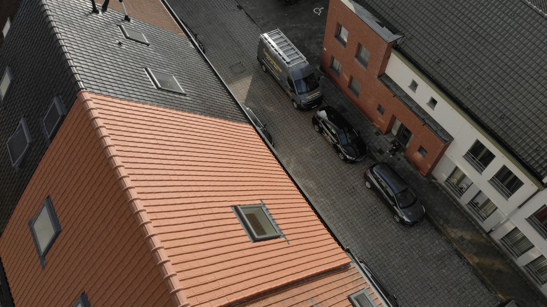 Het nieuwe sarkingdak in Gent in zijaanzicht, met de nieuwe pannen tot tegen de gevel van de buur