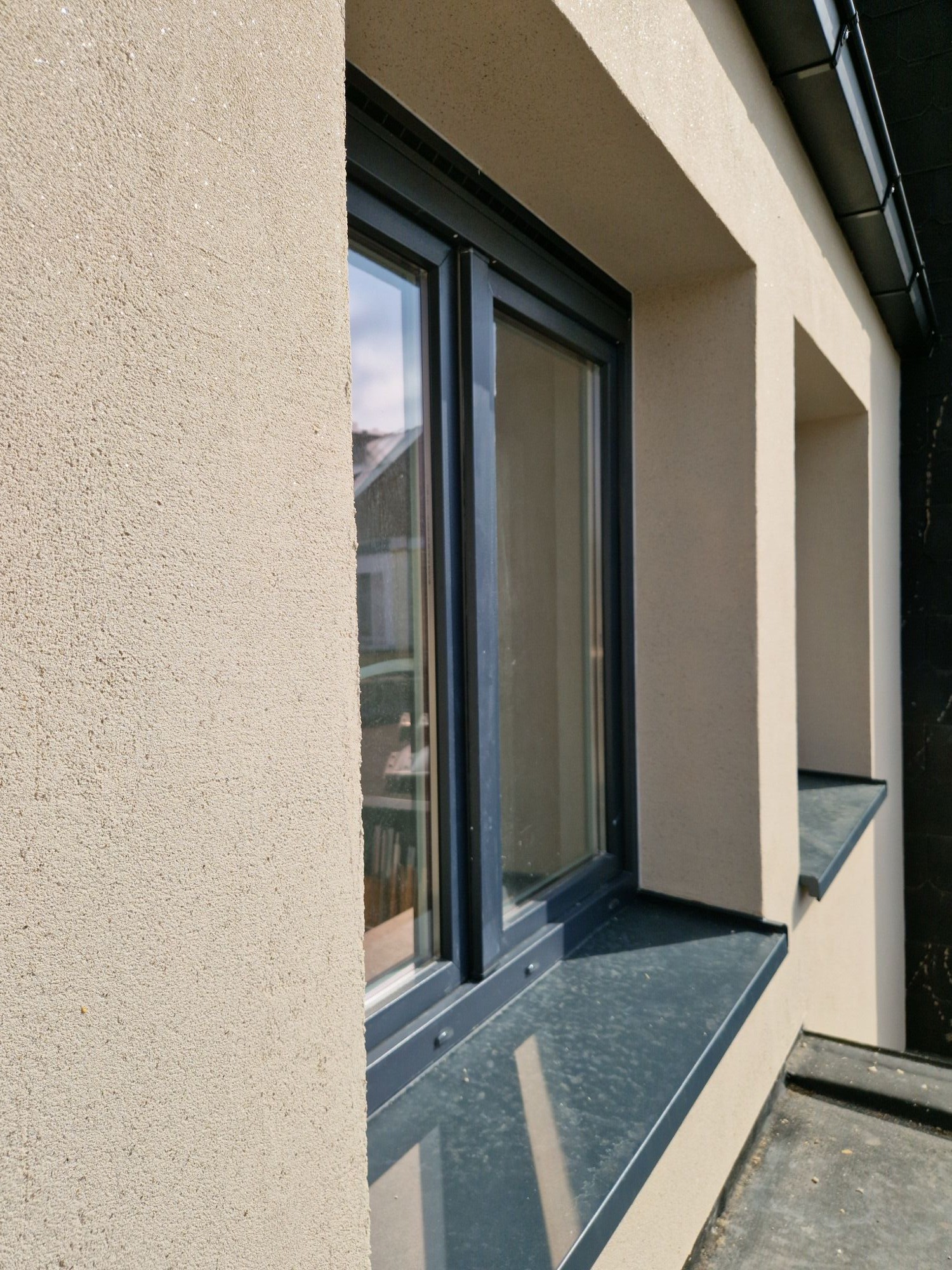 Detail van de sierpleister gevelafwerking rond het dakvenster, na de renovatie