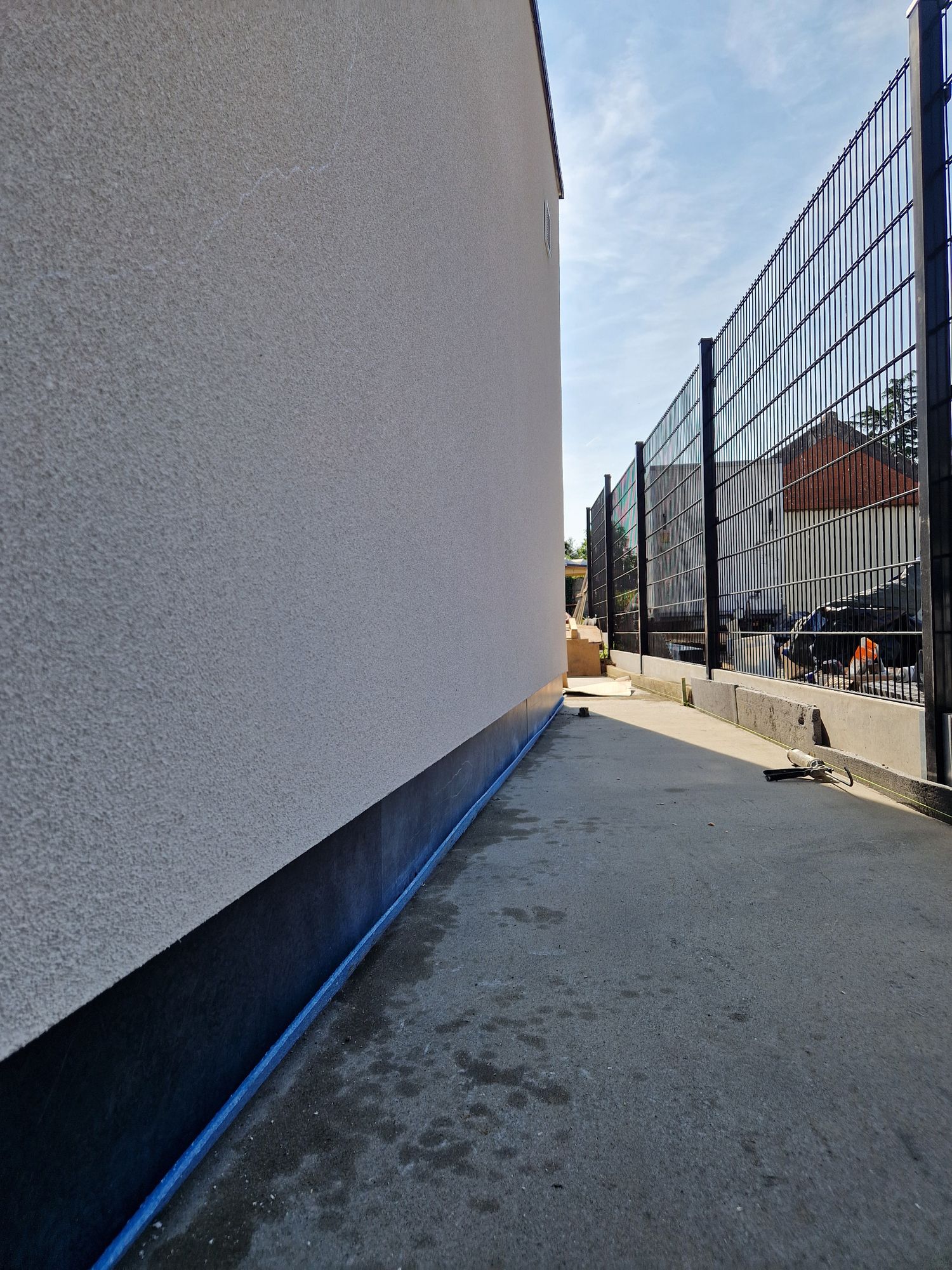 De zijgevel in Merelbeke met witte spuitkurk en een plint in blauwe steen