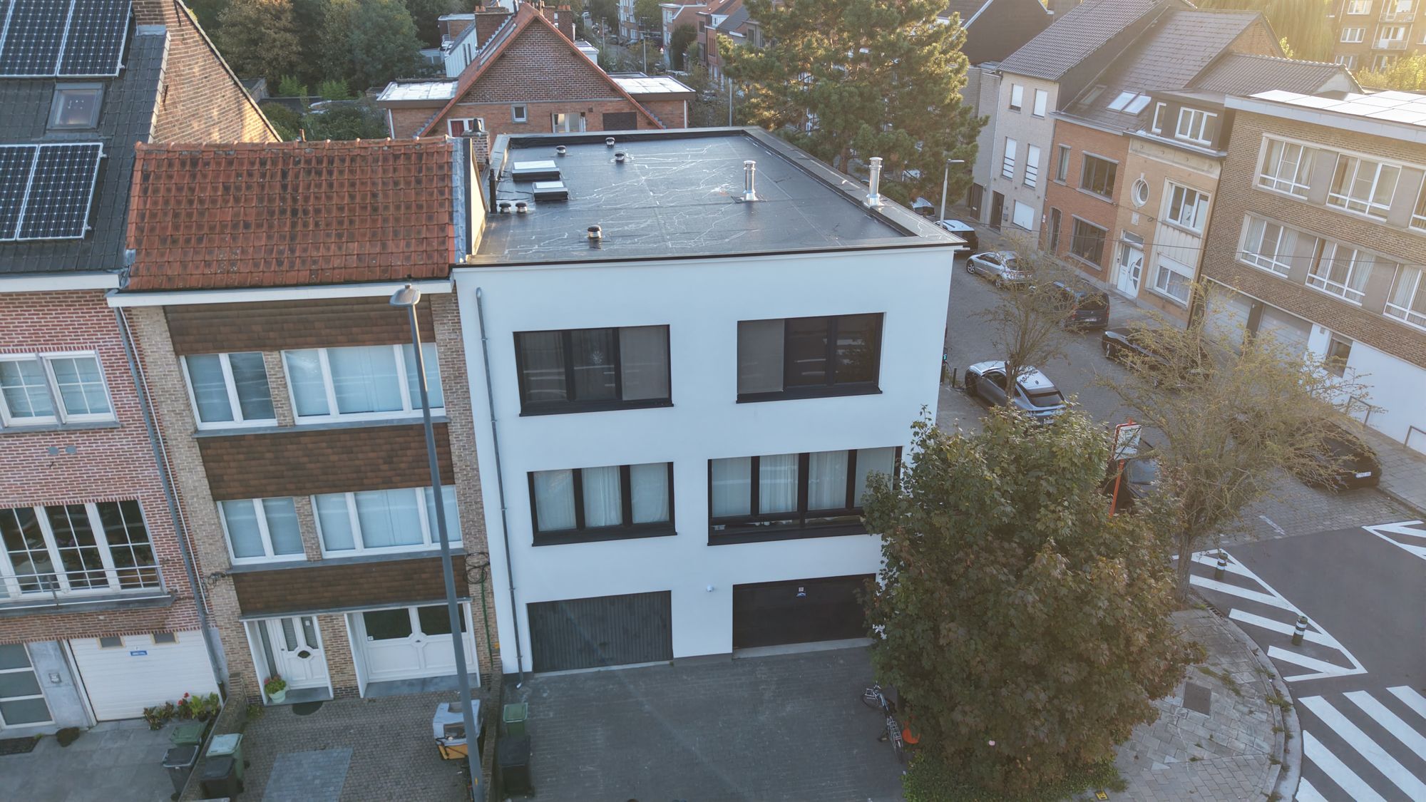 Luchtfoto van de straatgevel in Gent na de gevelisolatie, wit naast de bakstenen buurwoning