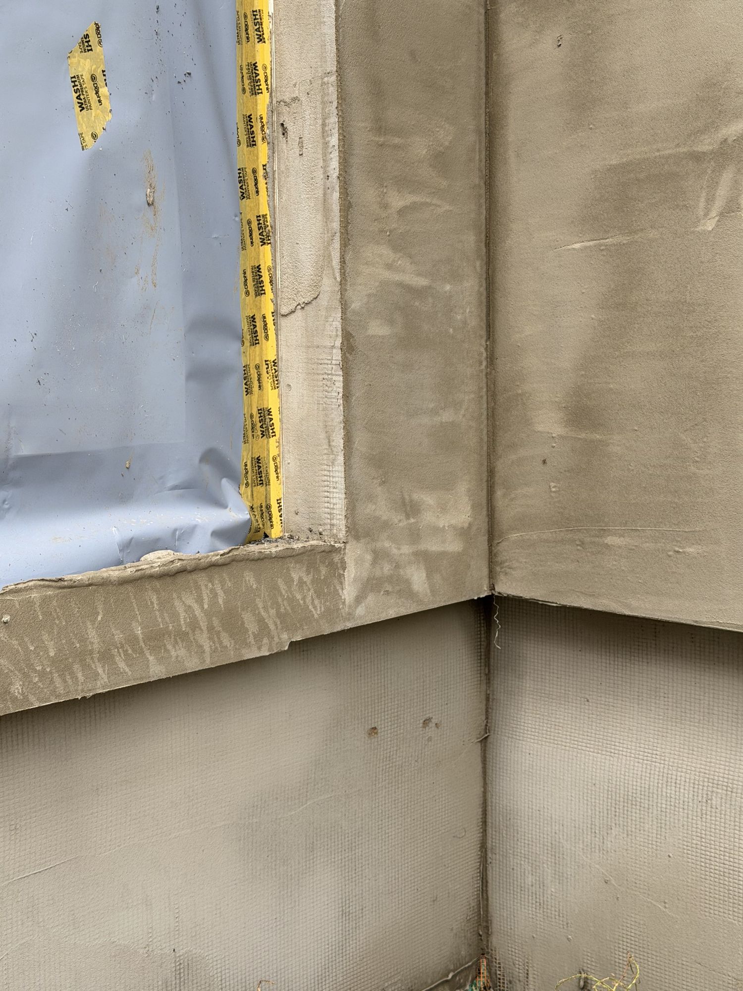 Het wapeningsnet in de basislaag op een hoek van de gevel in Brakel, voor de spuitkurk erop komt