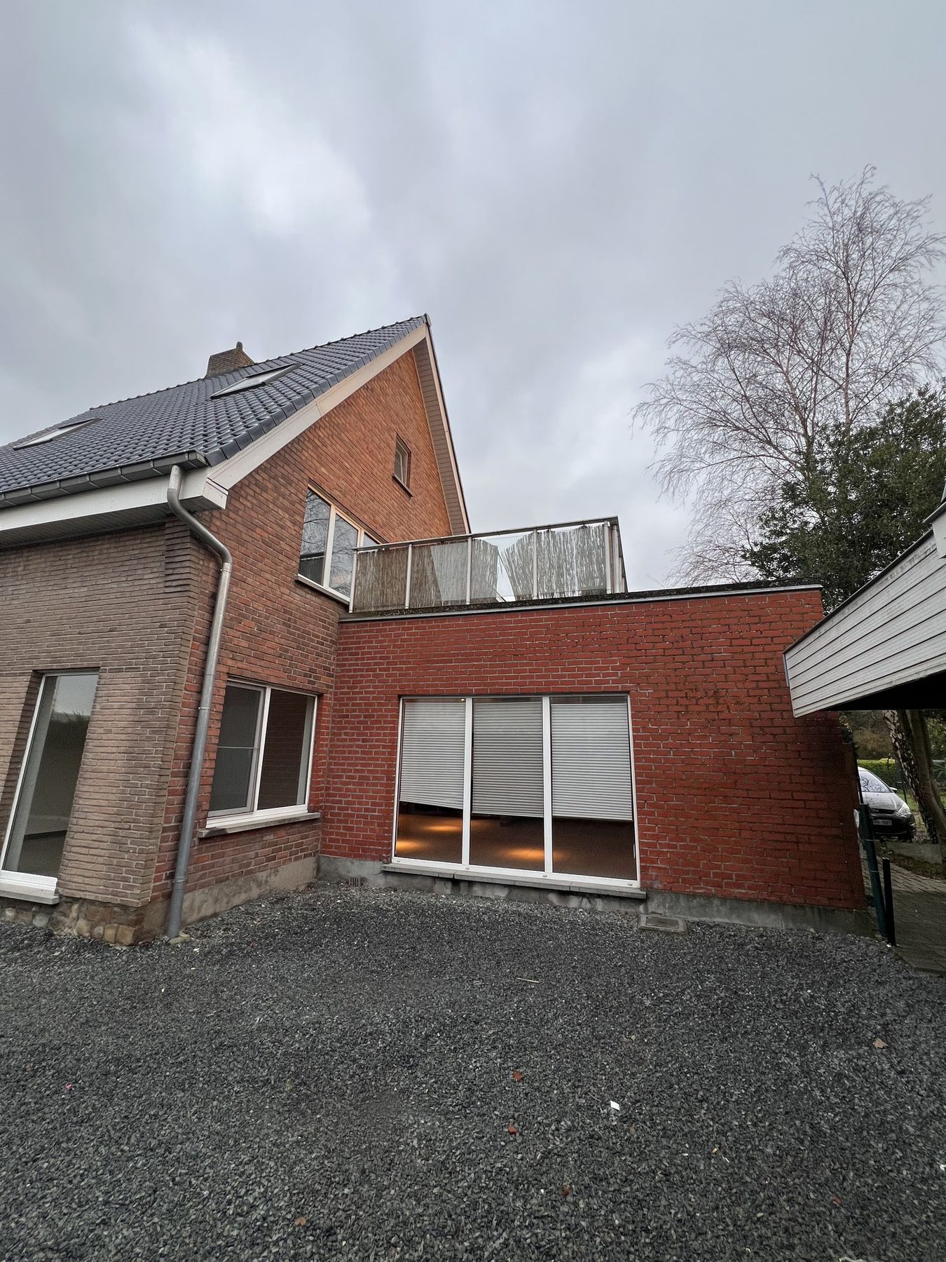 De zijgevel met grote raampartijen in Merelbeke voor de gevelisolatie