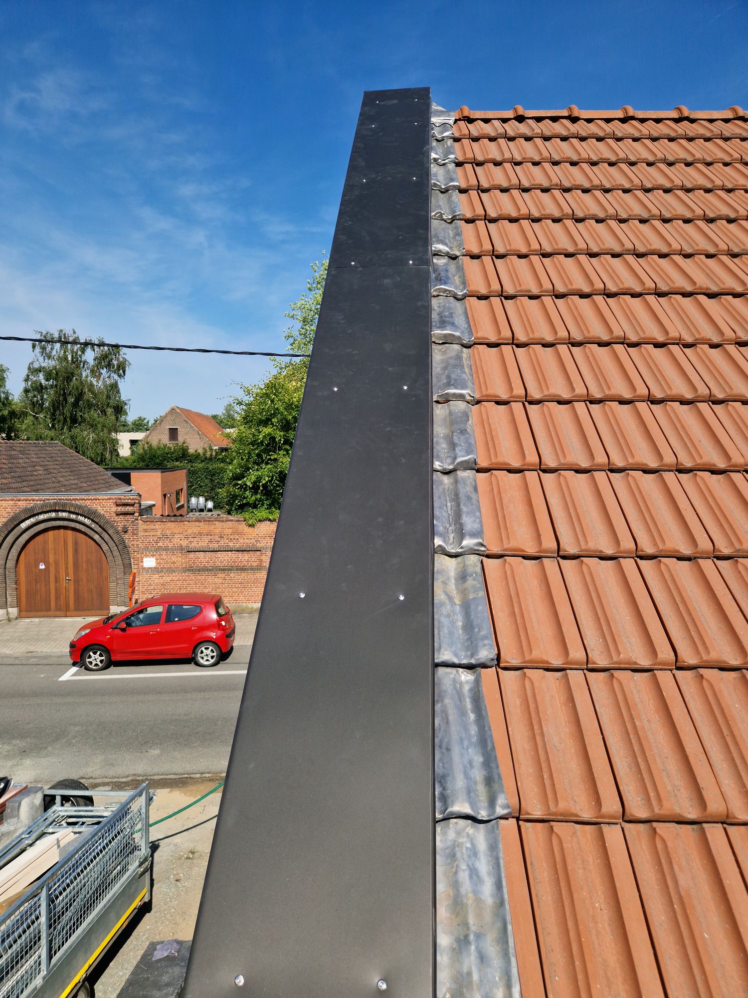 De verlengde dakrand met zinken profiel boven de geisoleerde gevel in Merelbeke